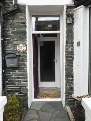 a white door on a brick building with a stone wall at Felltop Cottage in Keswick