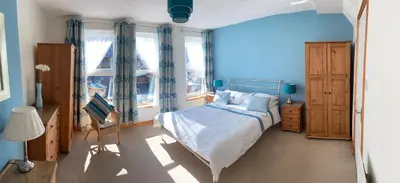 a blue bedroom with a bed and a tv in it at Felltop Cottage in Keswick