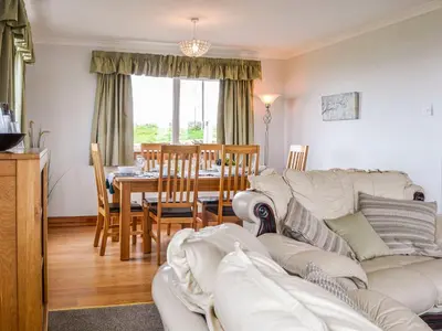 a living room with a couch and a dining room table at Auld Dairy Cottage in Drummore