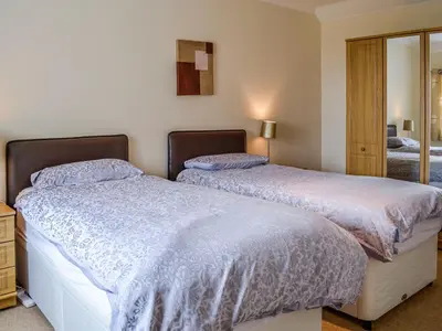 a bedroom with two beds and a mirror at Auld Dairy Cottage in Drummore