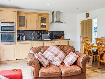 a living room with a couch and a kitchen at Mount Farm - The Stable in Harker