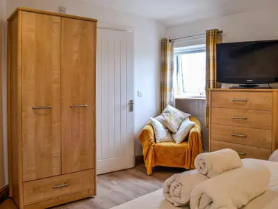 a bedroom with a tv and a dresser with a bed at Mount Farm - The Stable in Harker