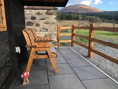a wooden chair sitting on a patio with a fence at 1 Bed Cabin in the Magical Galloway Forest Park in Newton Stewart