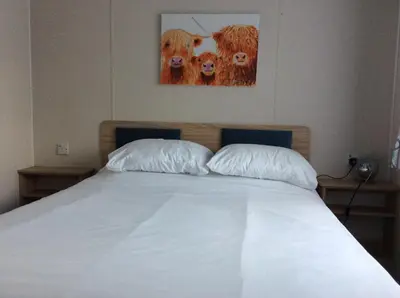 a bed with two pillows and a picture of cows at Lake District Western 2-Bed Cabin Pet Friendly in Wigton