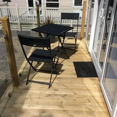 two chairs and a table on a porch at Lake District Western 2-Bed Cabin Pet Friendly in Wigton