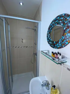 a bathroom with a shower and a sink and a mirror at Beachcomber in Garlieston