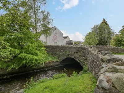 a stone bridge over a river with a building in the background at Ashness in Keswick