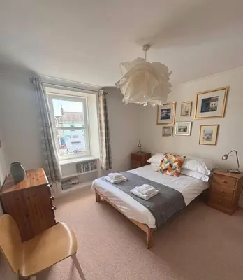 a bedroom with a bed with a chair and a window at Holiday House at 22, 3 bedroom cottage in historic Wigtown in Wigtown