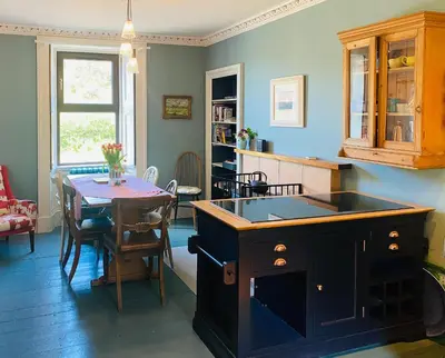 a kitchen and dining room with a table and a stove at Rosebank Cottage in Borgue