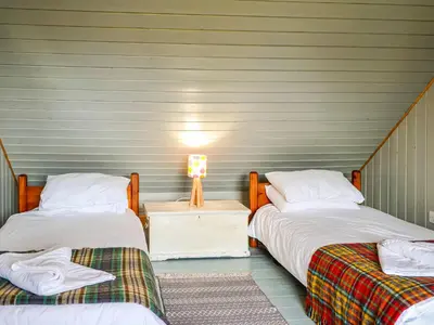 two beds sitting next to each other in a room at Rosebank Cottage in Borgue
