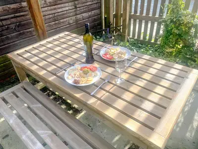 a picnic table with two plates of food and a bottle of wine at Rosebank Cottage in Borgue