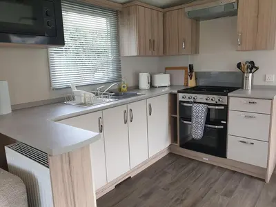 a kitchen with white cabinets and a stove top oven at Coral Cabin in Kippford