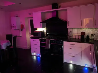 a kitchen with pink walls and a stove and cabinets at Sea-Renity - Self Catering Holiday Let in Douglas