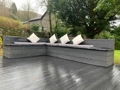 a bench with white pillows on a wooden deck at Wisteria in Ambleside