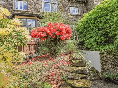 a garden with red flowers in front of a building at Wisteria in Ambleside