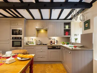 a kitchen with white cabinets and a wooden table at Stone Beck in Ambleside
