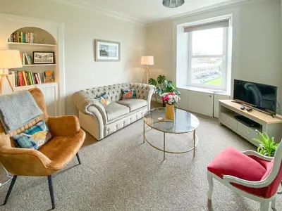 a living room with a couch and chairs and a tv at 9A Church Place in Kirkcudbright