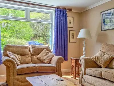 a living room with a couch and a window at Craik Forestry Cottage in Teviothead