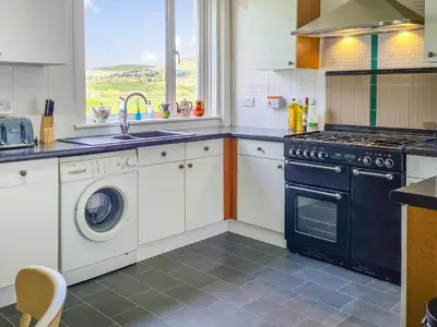 a kitchen with a washing machine and a sink at Craik Forestry Cottage in Teviothead
