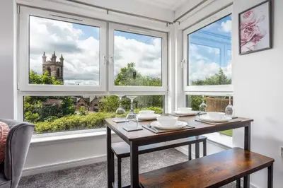 a dining room with a table and two windows at Walker Suite No 60 - Donnini Apartments in Kilmarnock
