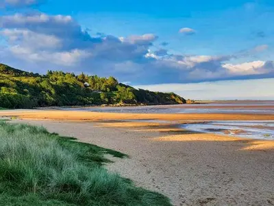 a beach with sand and trees in the distance at Beautiful 3BR Lodge - Stunning Beach and Golf Location - Pass the Keys in Dalbeattie