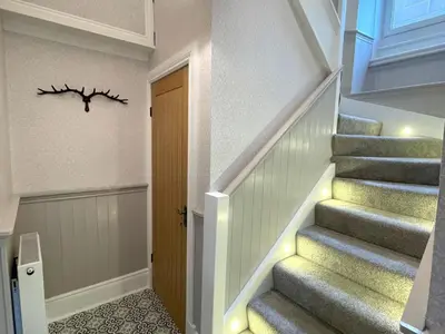 a hallway with stairs with a branch on the wall at Beautifully Presented 3BR Luxury Apartment - Pass the Keys in Kirkcudbright