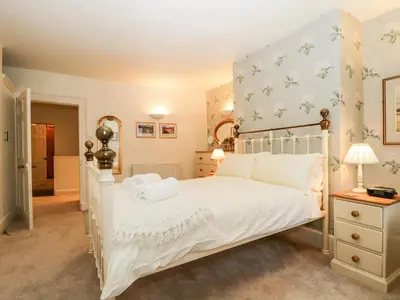 a bedroom with a white bed and a blue wall at Raphael's Cottage in Keswick