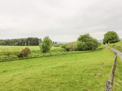 a field with a fence and a road at Strathannan in Moffat