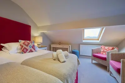 a bedroom with two beds and a window and a chair at Riverside Park 6 in Keswick