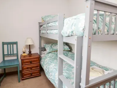 a bedroom with a bunk bed and a chair at Lavender Cottage in Penrith