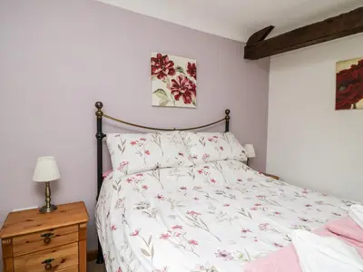 a bedroom with a bed and a wooden dresser at Lavender Cottage in Penrith