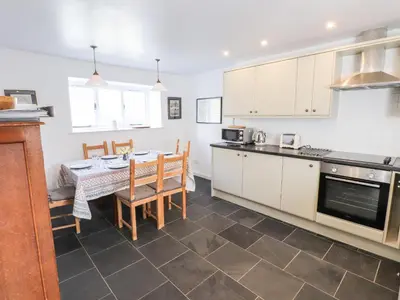a kitchen with white cabinets and a table with chairs at One Town End in Penrith
