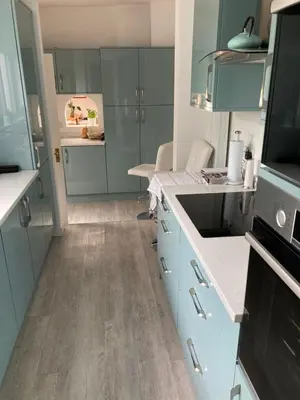 a kitchen with blue cabinets and wooden floors at Rose Cottage in Prestwick