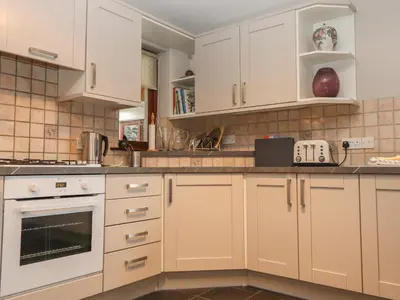 a kitchen with white cabinets and white appliances at Beech Nook in Keswick
