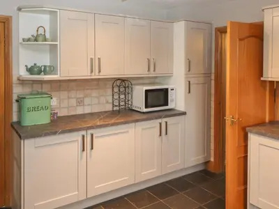 a kitchen with white cabinets and a microwave at Beech Nook in Keswick