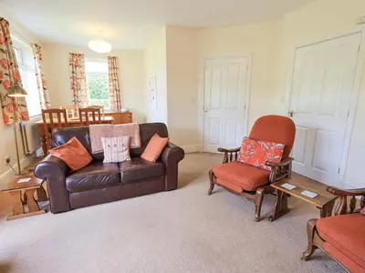 a living room with a leather couch and two chairs at Limhus Cottage in Keswick