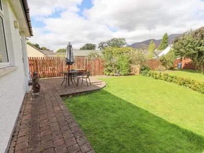 a patio with a table and an umbrella in a yard at Limhus Cottage in Keswick