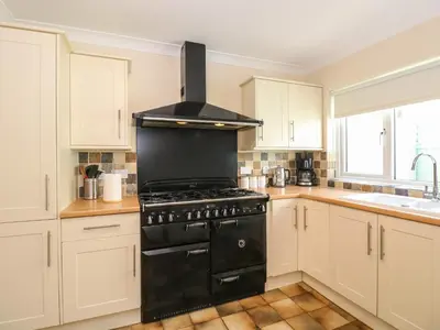 a black stove in a kitchen with white cabinets at Inglewood in Keswick