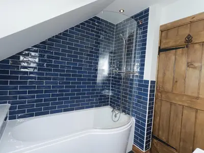 a bathroom with blue tiles and a tub at Lucys cottage in Canonbie