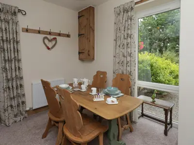 a dining room with a table and chairs and a window at Lucys cottage in Canonbie
