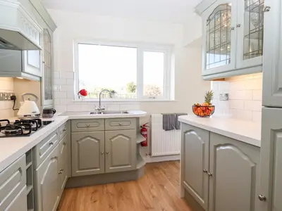a kitchen with white cabinets and a sink and a window at Pooley Howe in Keswick