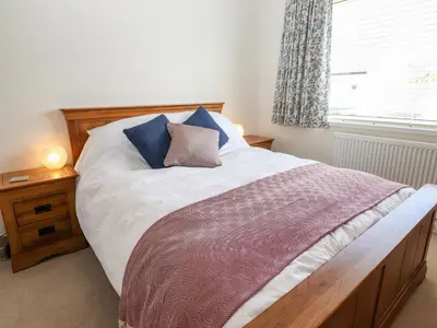 a bedroom with a bed with a wooden headboard and a window at Pooley Howe in Keswick