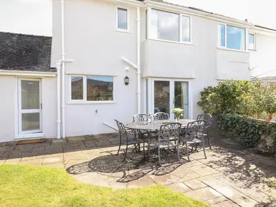 a patio with a table and chairs in front of a house at Pooley Howe in Keswick