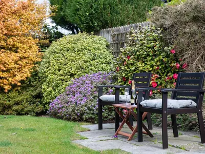 two chairs and a table in a garden with flowers at Pooley Howe in Keswick