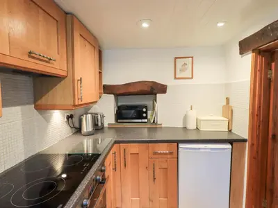 a kitchen with wooden cabinets and a black counter top at Squirrel Cottage in Keswick