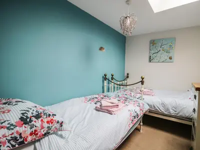 a bedroom with two beds and a blue wall at Daisy Cottage in Penrith