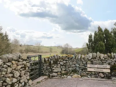 a stone wall with a gate and a sign at Daisy Cottage in Penrith