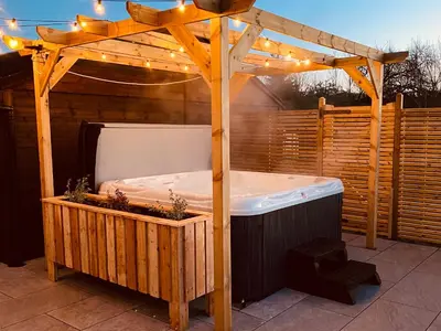 a wooden gazebo with a hot tub on a patio at Daisy Cottage in Penrith