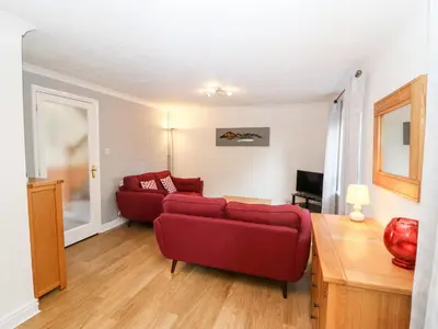 a living room with a red couch and a table at Annes Cottage in Keswick