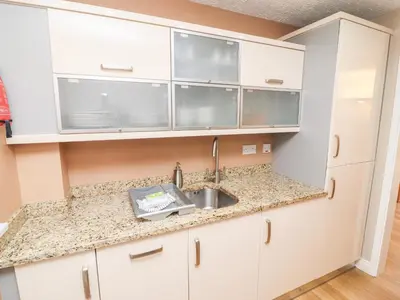 a kitchen with white cabinets and a sink at Annes Cottage in Keswick